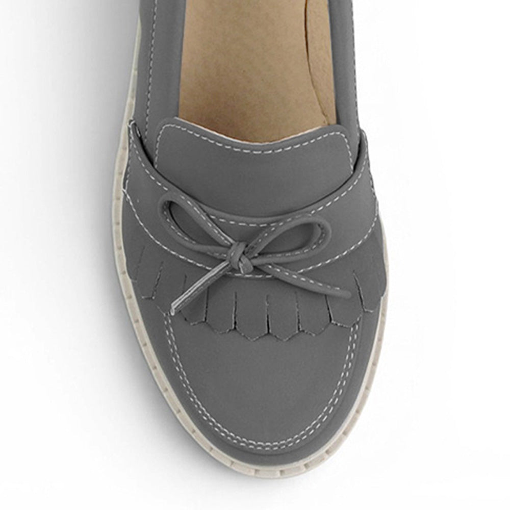 Vista del detalle en moño y flecos del mocasín gris para dama con tacón medio 8 cm 