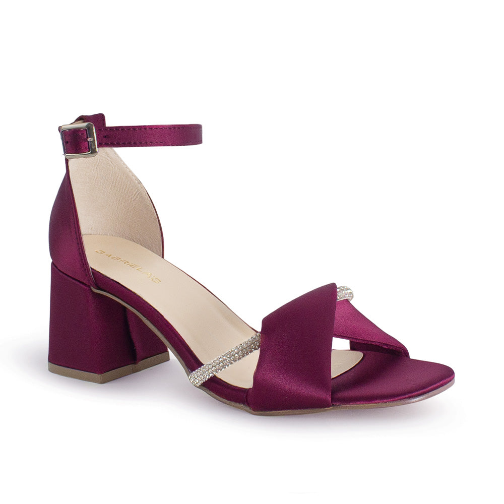 Vista diagonal de zapatilla vino para mujer con banda cruzada de pedrería y tacón ancho medio de 7cm