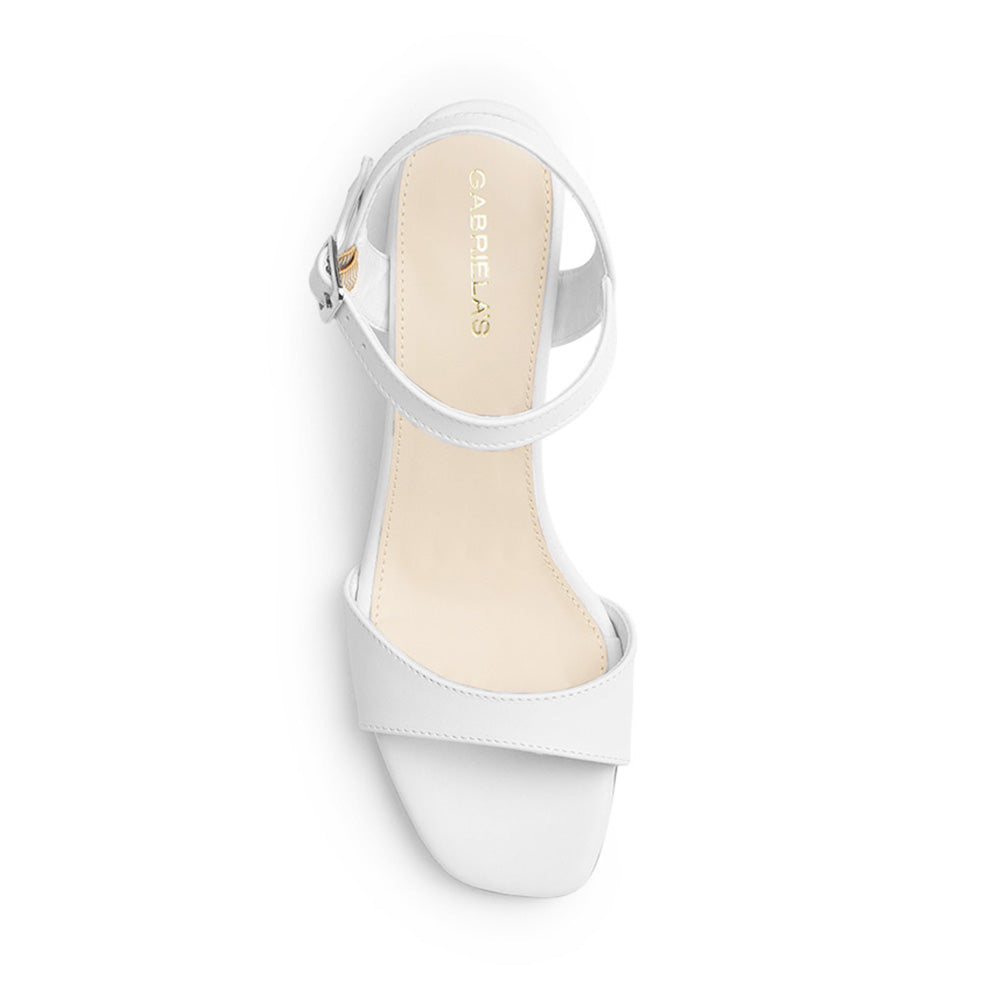 Vista superior de zapatilla blanca para mujer de diseño descubierto con pulsera ajustable y tira al frente 
