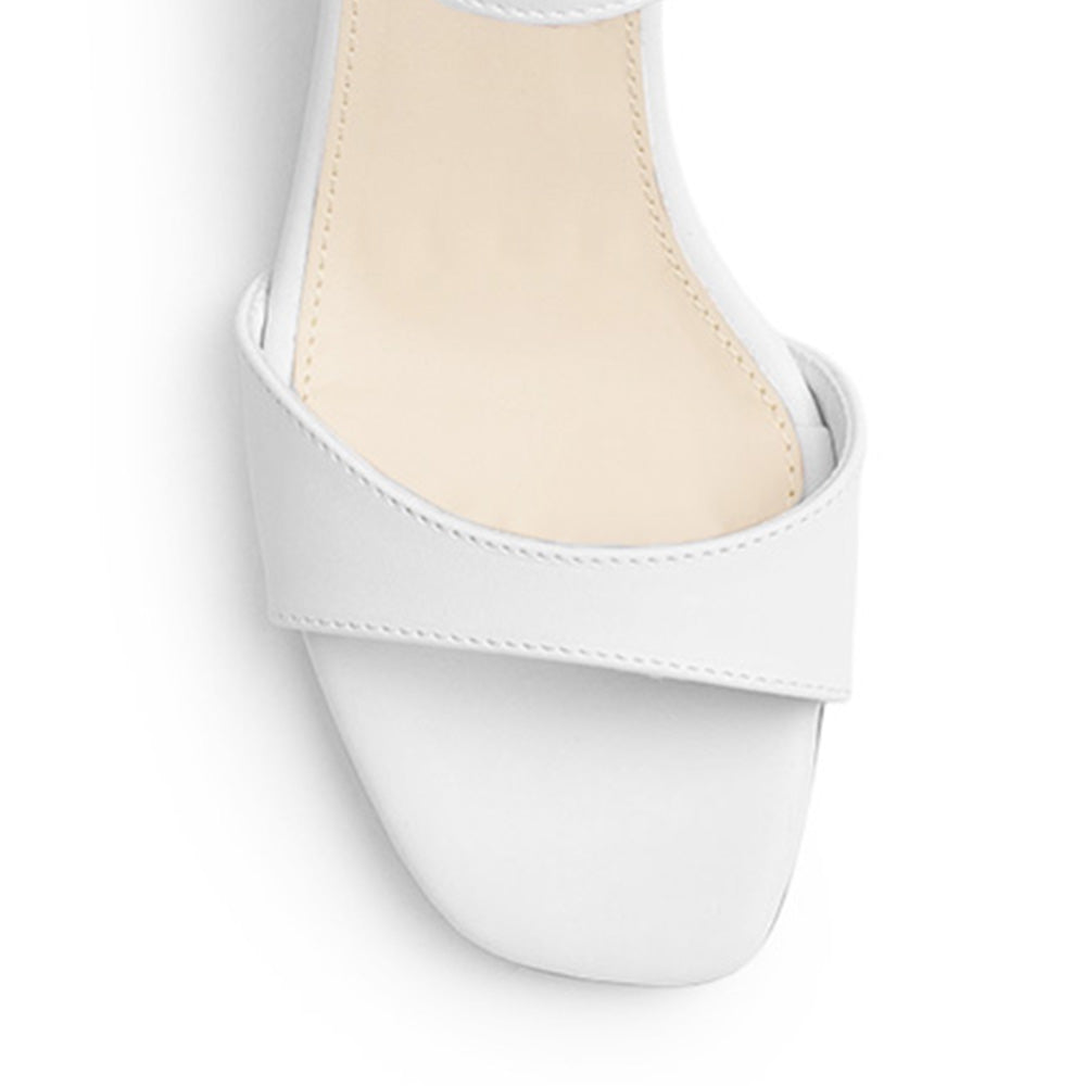 Vista de material cabra sintético en zapatilla blanca para mujer con tira frontal pulsera ajustable y tacón grueso de 7cm
