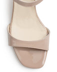 Vista de material charol en zapatilla nude para mujer con tira frontal pulsera ajustable y tacón grueso de 7cm