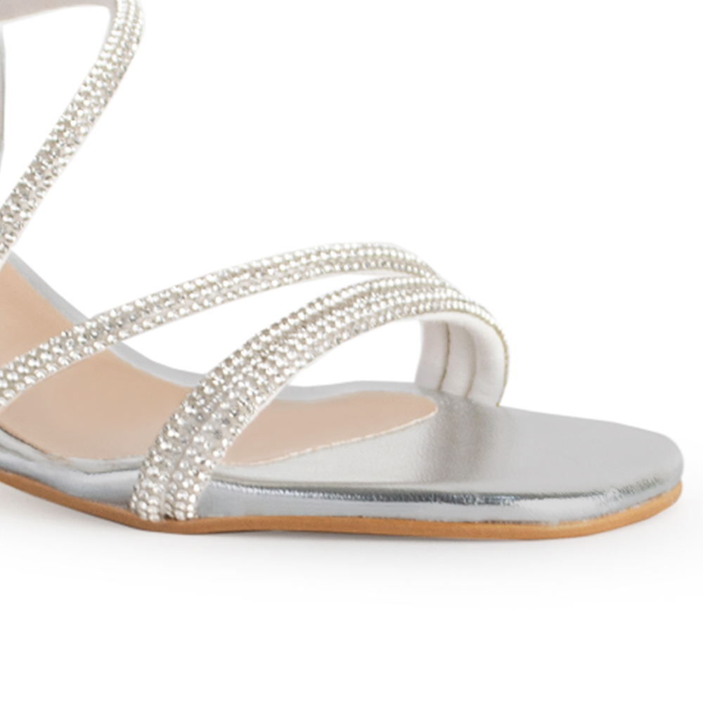 Vista a detalle de zapatilla plata para mujer con tiras brillantes y tacón bajo de 6cm