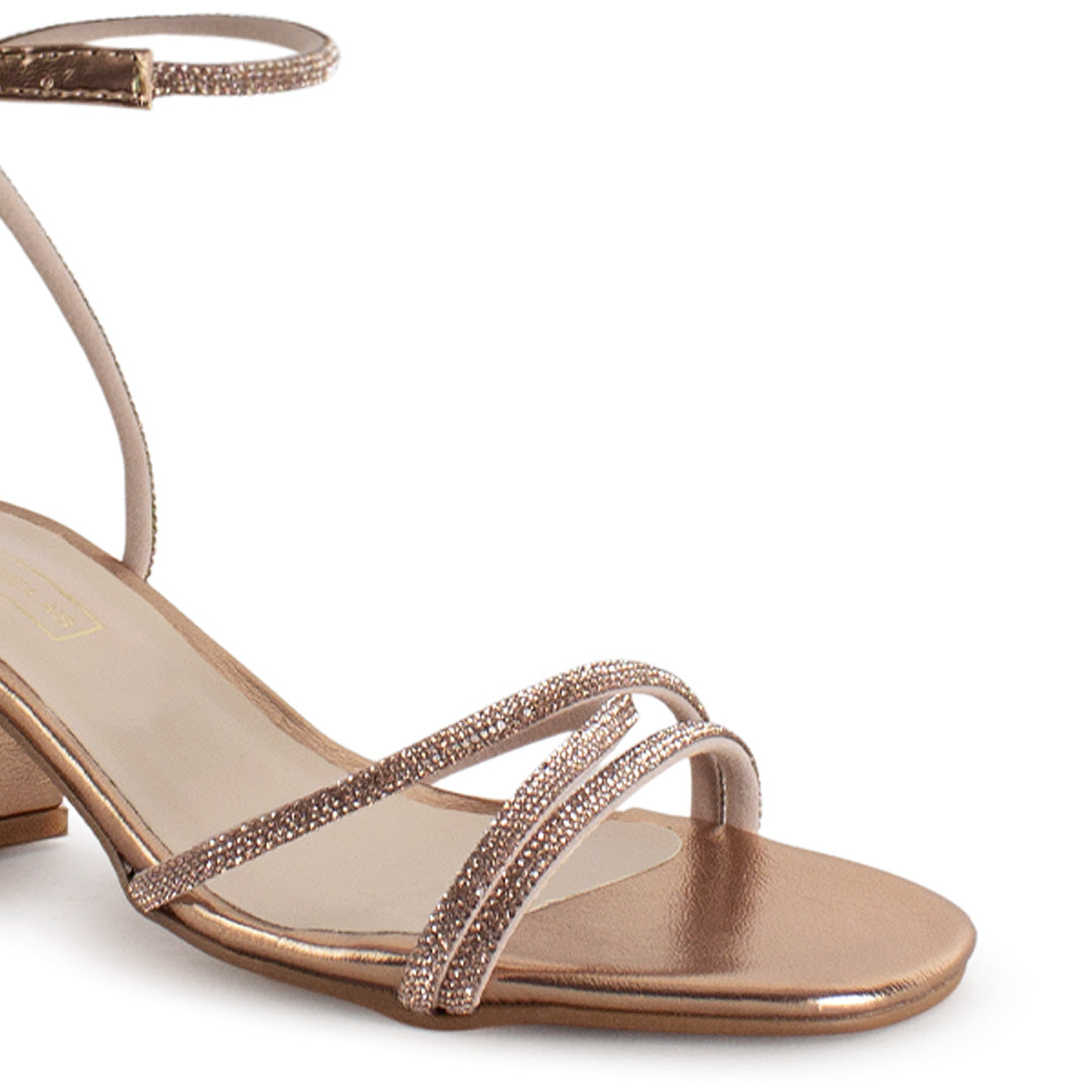 Vista a detalle de diseño descubierto con tiras de pedrería en zapatilla oro rosa para mujer con tacón bajo de 6cm
