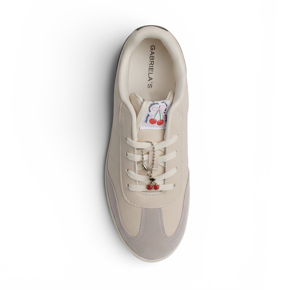 Vista superior de tenis beige con negro de punta redonda para mujer con adorno colgante en las agujetas 
