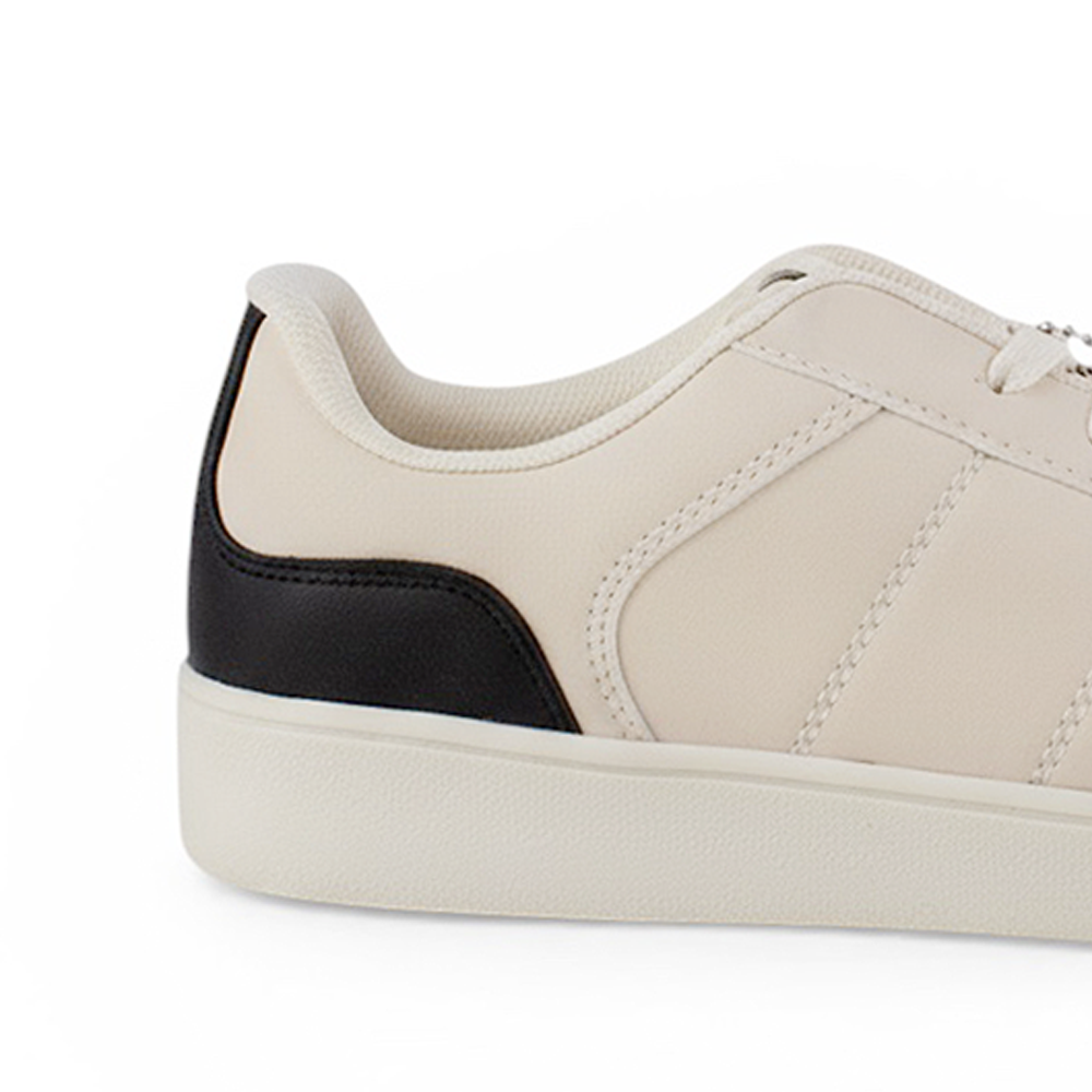 Vista trasera de suela baja en tenis beige con negro para mujer con ajuste de agujetas y colgante 