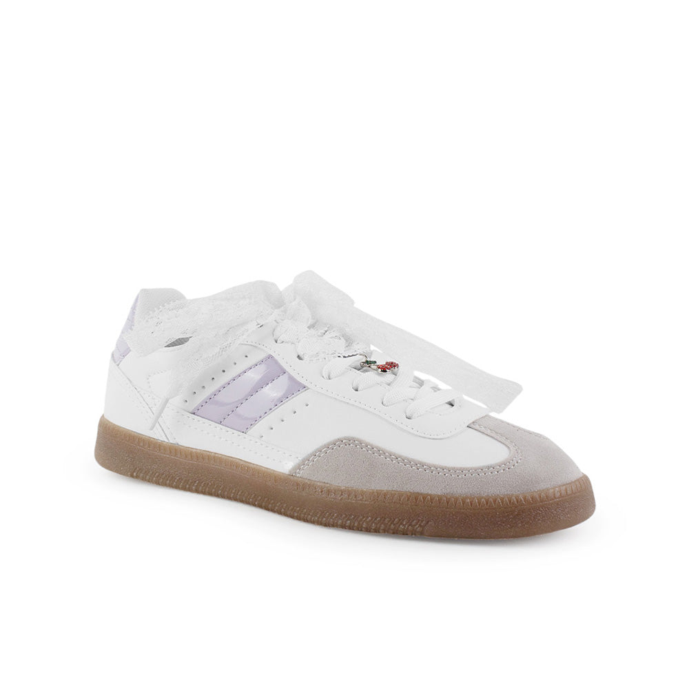 Vista diagonal de tenis blanco con morado para mujer con colgante en agujetas y suela baja de punta redonda