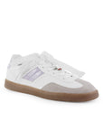 Vista diagonal de tenis blanco con morado para mujer con colgante en agujetas y suela baja de punta redonda