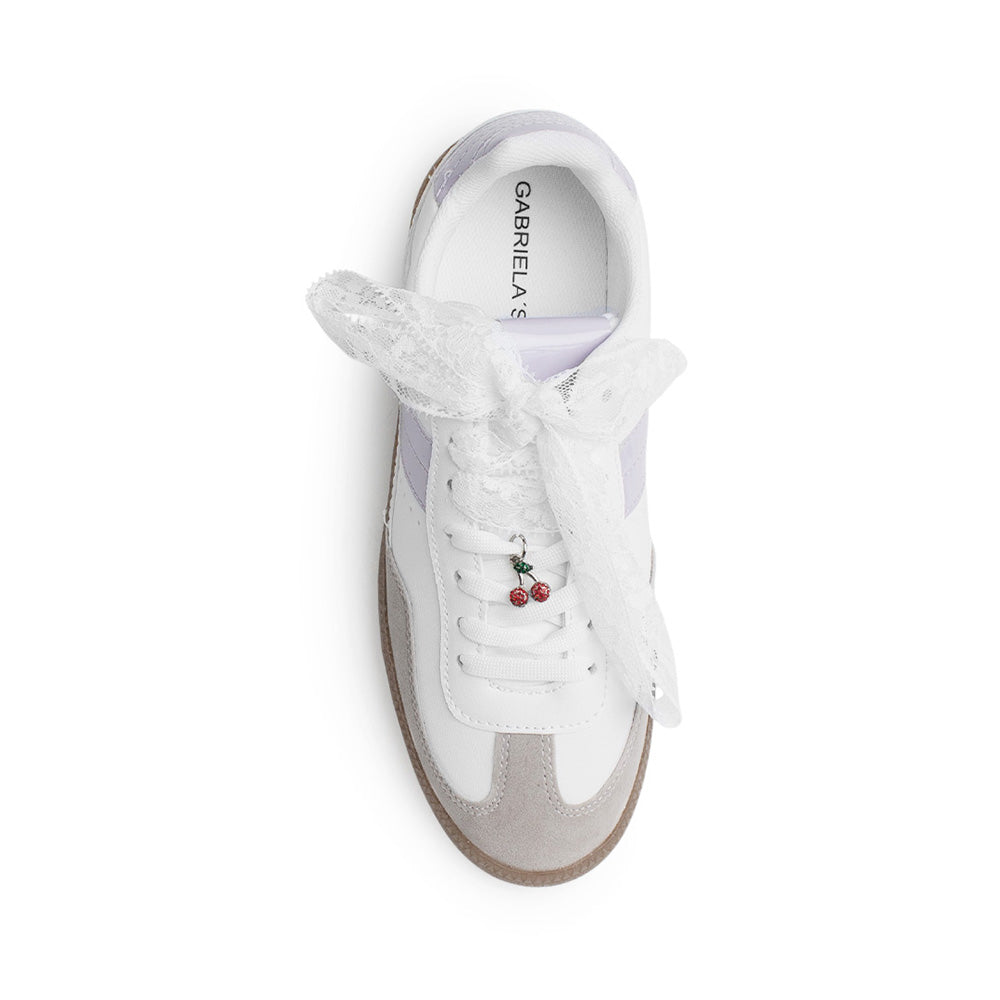 Vista superior de tenis blanco con morado de punta redonda para mujer con adorno colgante en las agujetas 