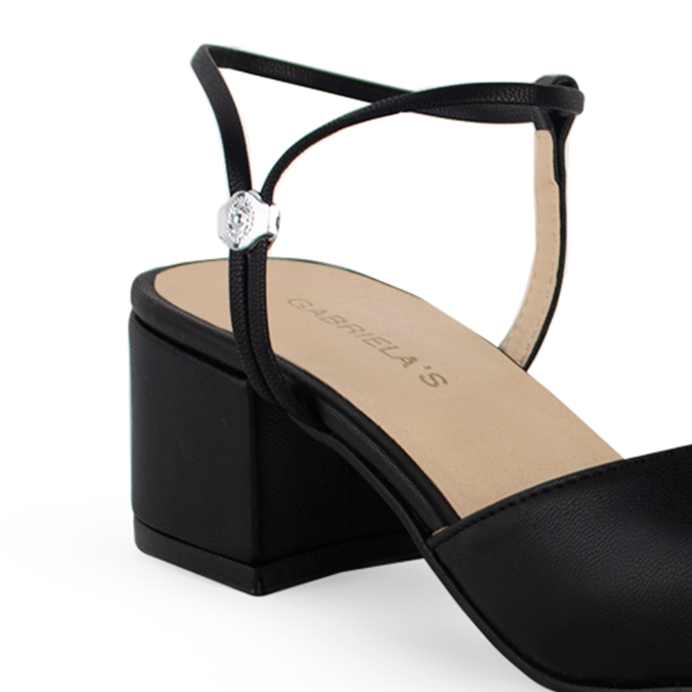 Vista a detalle de correa ajustable en zapatilla negra para mujer con tacón bajo de 5cm