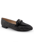 Vista diagonal de mocasín negro de meter para mujer con herraje decorativo en empeine y punta fina de piso
