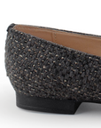 Vista trasera de mocasín negro de piso para mujer con herraje decorativo y punta fina 