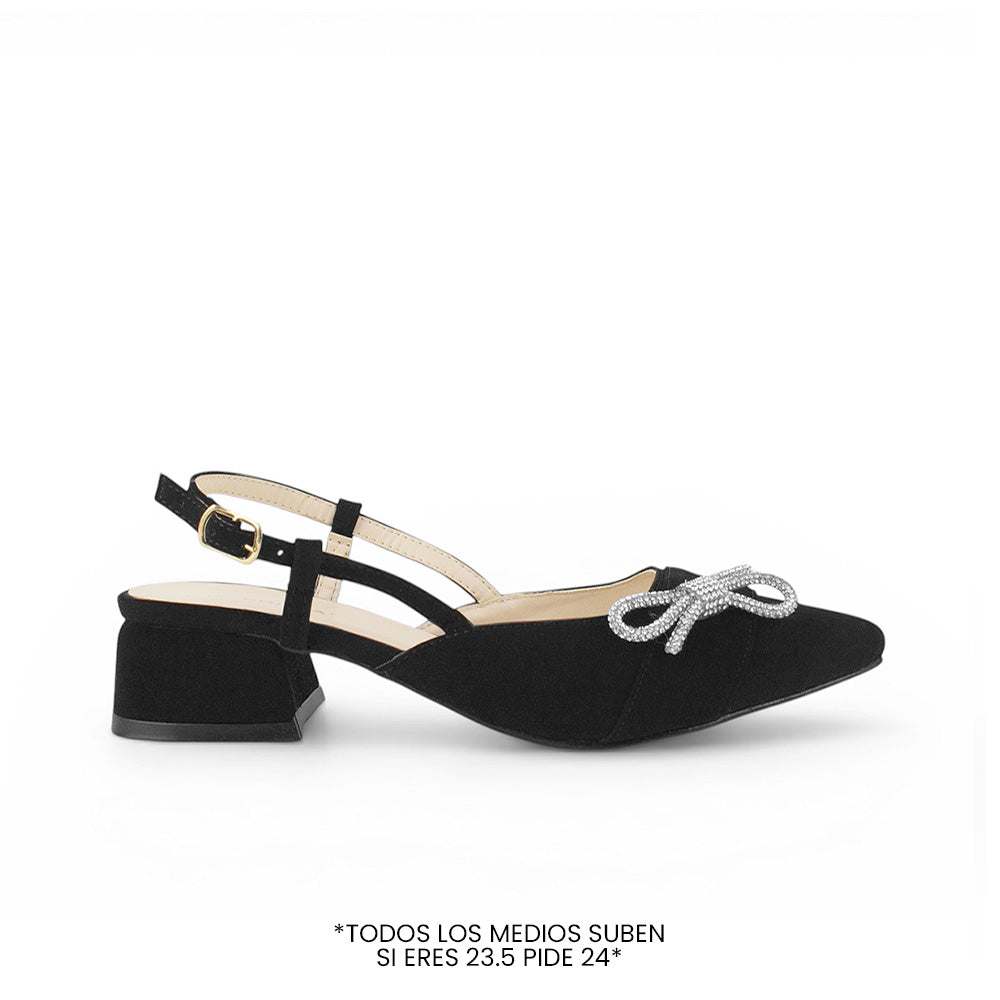 Vista lateral de zapatilla negra  destalonada para mujer con moño de pedrería punta fina cerrada y tacón bajo de 4cm