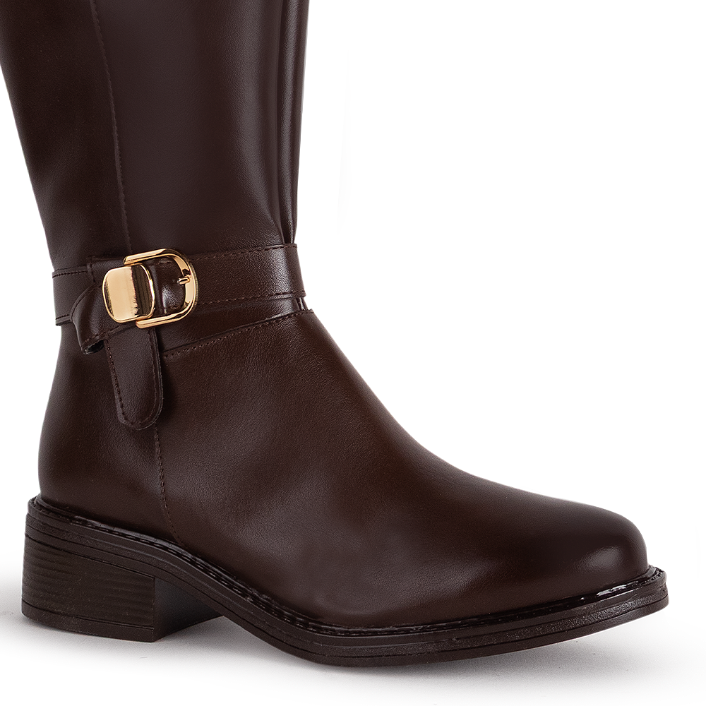 Detalle del material sintético en la bota café para dama con herraje metálico decorativo y tacón bajo 4cm  