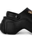 Vista trasera de la plataforma media 7cm en la sandalia negra con pulsera ajustable y charms decorativos para dama 