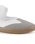 Detalle del material sintético en tenis blanco para dama, pulsera ajustable al tobillo y suela baja 