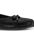 Detalle del material sintético en flats negro con moño decorativo y suela de piso para dama 