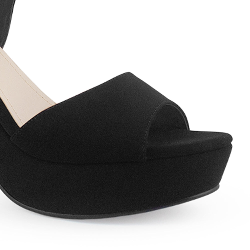 Vista a detalle de zapatilla negra para mujer con diseño abierto pulsera ajustable y tacón de 10cm