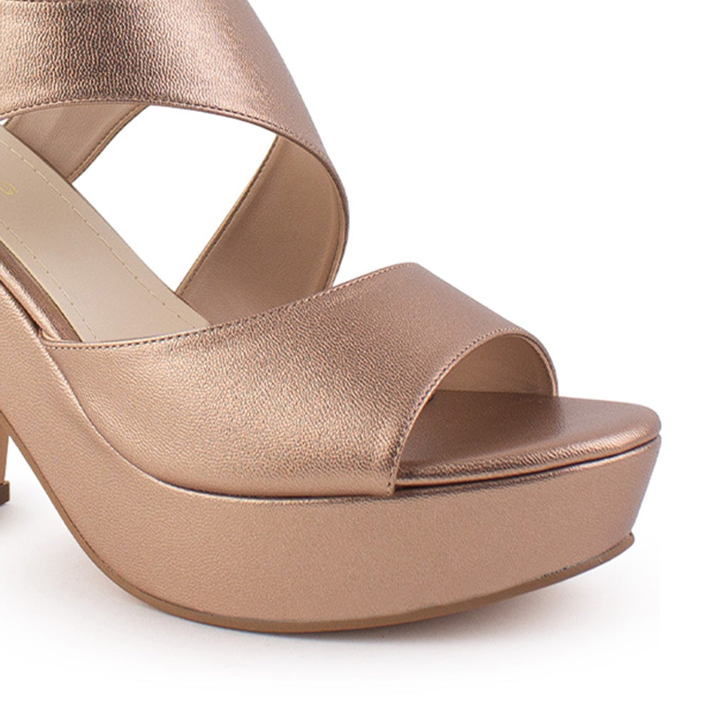 Vista a detalle de zapatilla oro rosado para mujer de diseño abierto con pulsera ajustable al tobillo y tacón medio de 10cm
