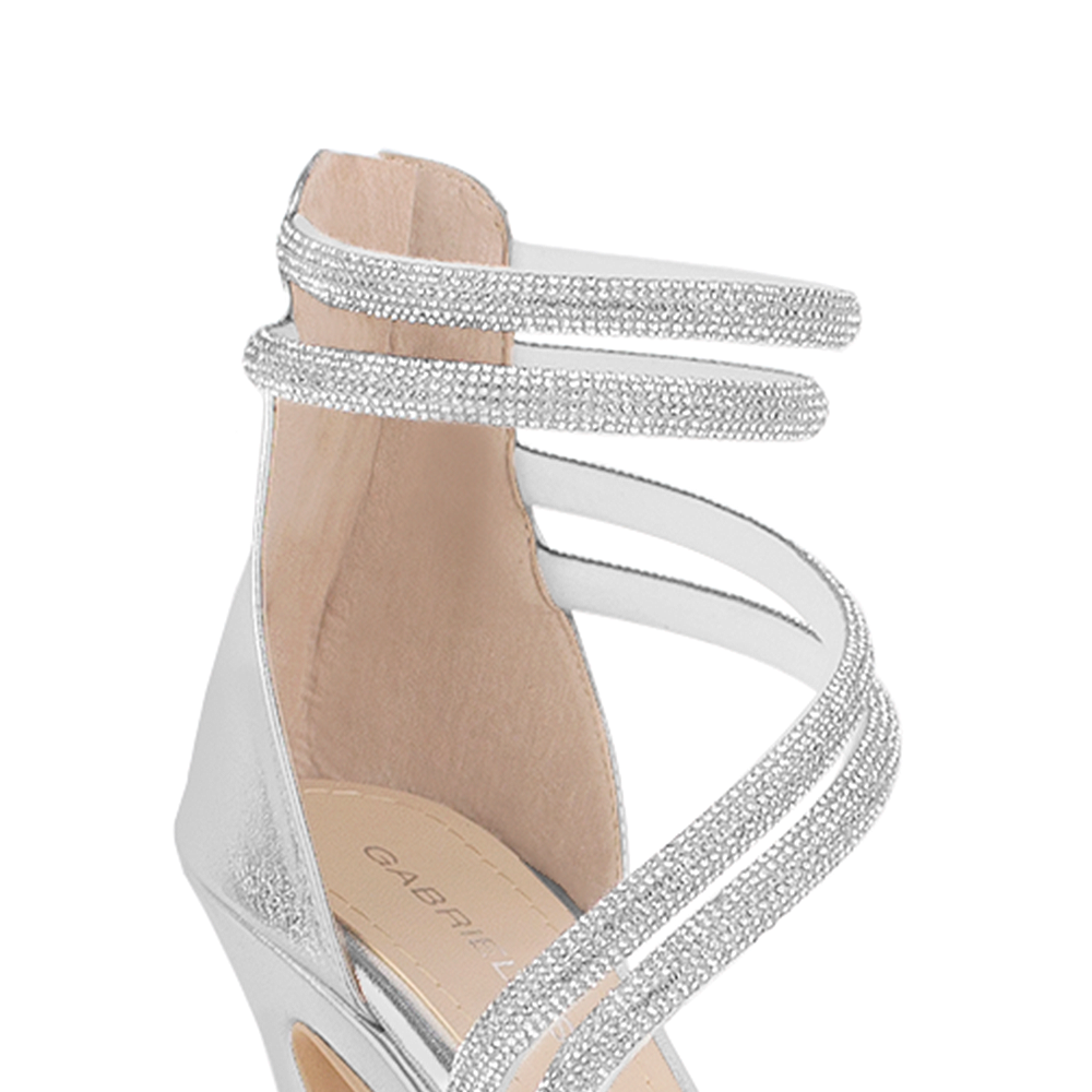 Vista a detalle de pulsera con pedrería en zapatilla plateada para mujer con tacón alto delgado de 12cm