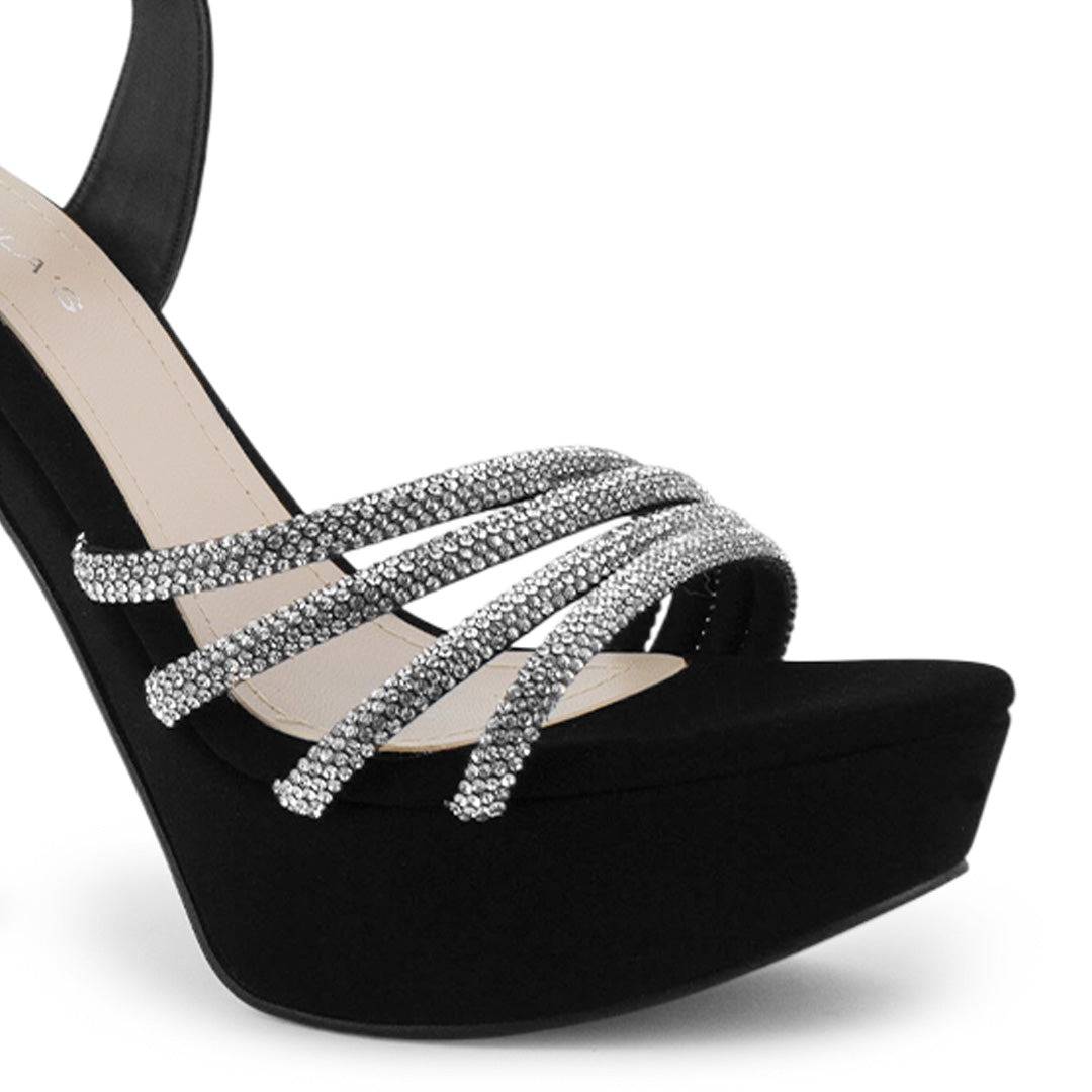 Vista a detalle de tiras con pedrería zapatilla negra para mujer con pulsera ajustable y tacón alto delgado de 13cm