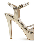 Vista trasera de tacón alto delgado de 13cm en zapatilla dorada de diseño descubierto para mujer con pedrería y pulsera ajustable al tobillo