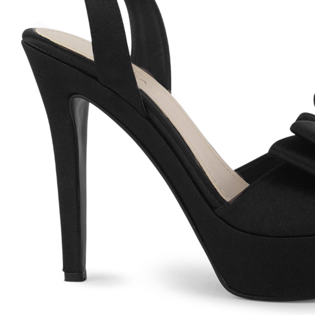 Vista trasera del tacón alto 12cm en zapatilla negra con plataforma, pulsera ajustable al tobillo punta abierta y moño para dama 