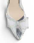 Vista de material charol en zapatilla plateada transparente tipo stiletto con moño en la punta para mujer con tacón medio de 9cm
