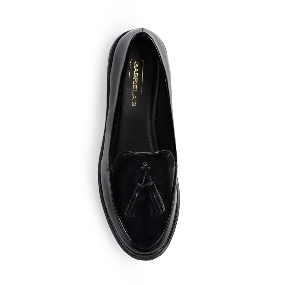 Vista superior del mocasín negro de charol con borlas decorativas para dama y suela de piso 