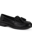 Vista diagonal del mocasín negro de material sintético con relieve para dama con suela de piso y borlas decorativas
