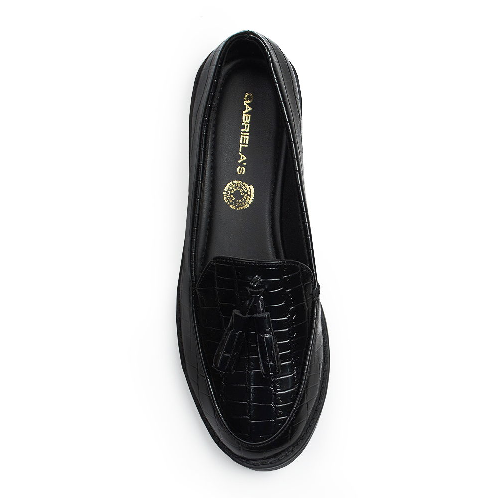 Vista superior del mocasín negro de material sintético con relieve, borlas decorativas para dama y suela de piso 