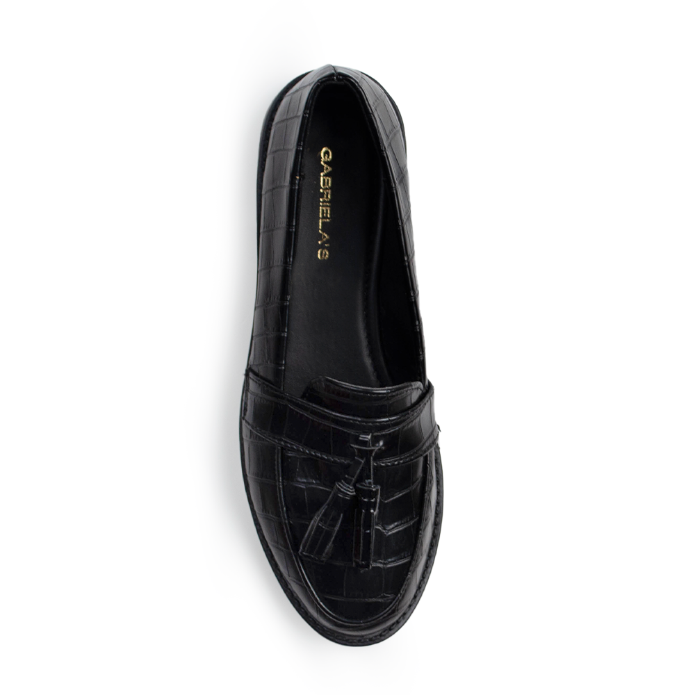 Vista superior de mocasín negro de piso para mujer con borlas decorativas en empeine de meter