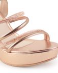 Vista a detalle de zapatilla oro rosado para mujer con pulsera, tiras de pedrería y tacón ancho medio de 10cm
