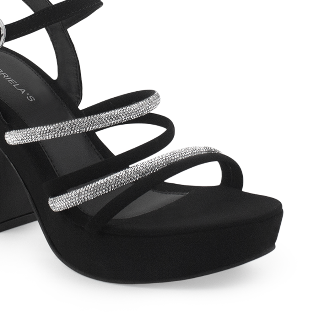 Vista a detalle de zapatilla negra para mujer con pulsera, tiras de pedrería y tacón ancho medio de 10cm