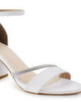 detalle del material cabra sintético en zapatillas blancas de tacón medio 7cm con detalles brillantes y pulsera al tobillo para dama