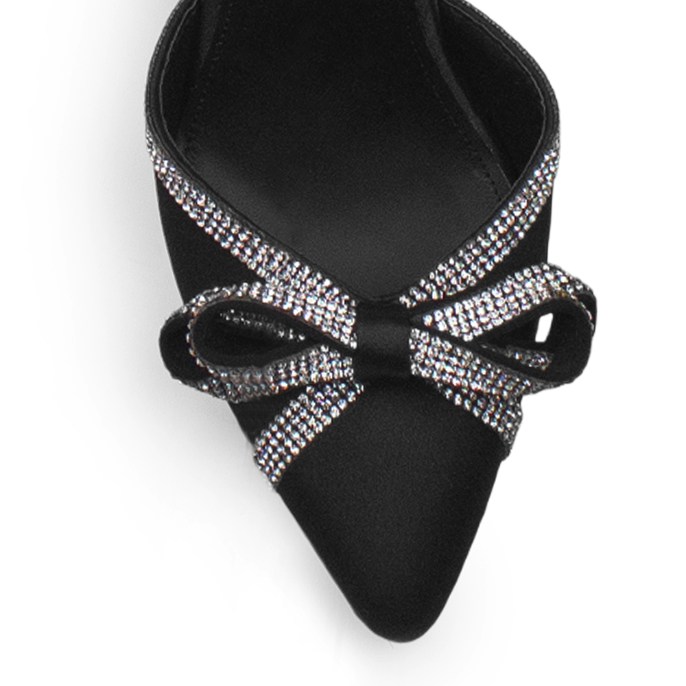Vista de material shantung en zapatilla con punta fina, moño de pedrería y tacón de 7cm color negro 