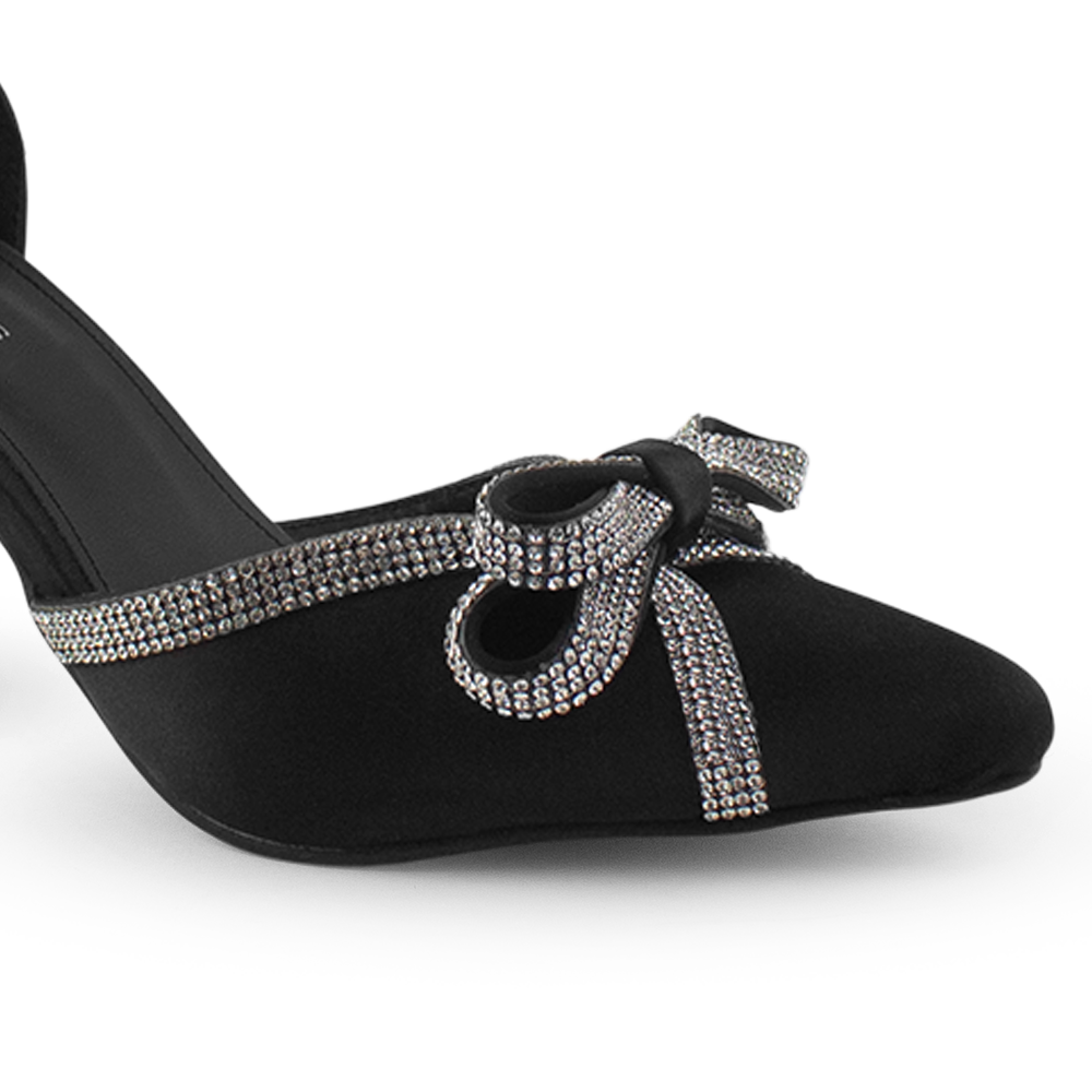 Vista a detalle de moño con pedrería y punta fina en zapatilla negra para mujer 