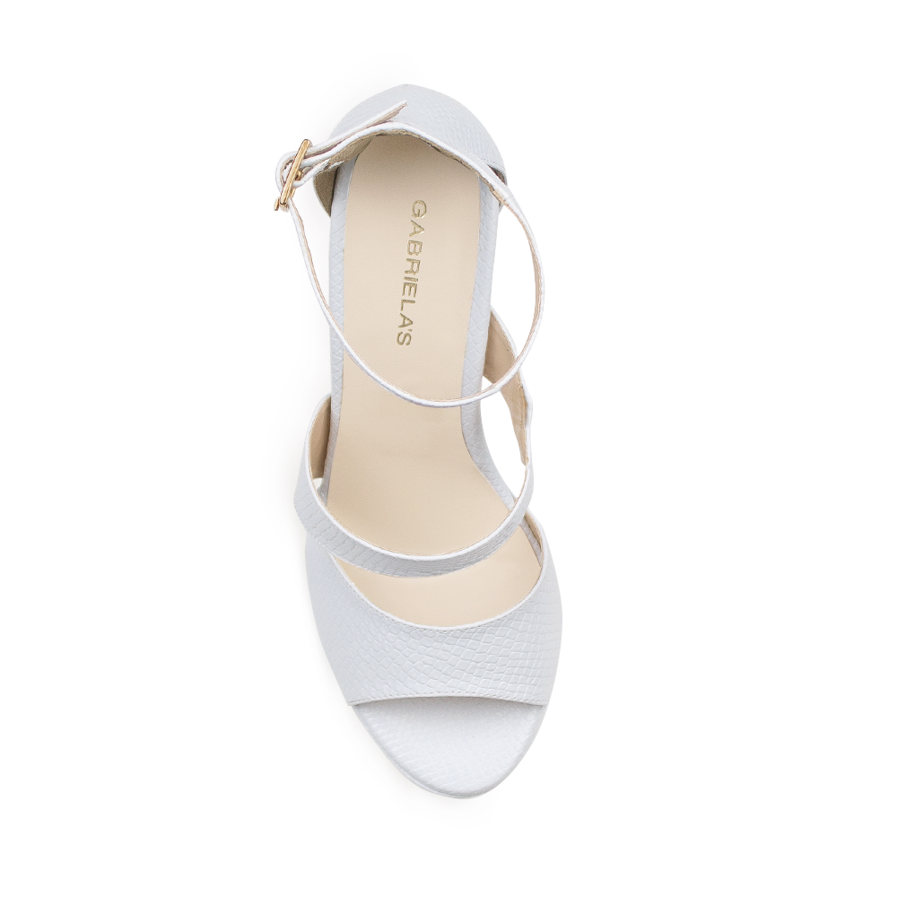 Vista superior de zapatilla blanca con pulsera ajustable al tobillo y diseño descubierto