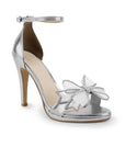 Vista diagonal de zapatilla con pulsera ajustable, moño con brillos y tacón de 10cm para mujer en color plata