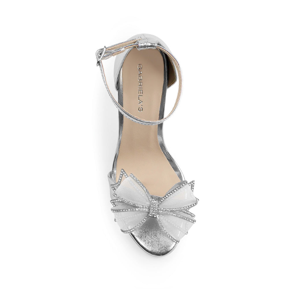 Vista superior de zapatilla plata para mujer con pulsera ajustable y moño con pedrería 