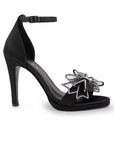 Vista lateral de zapatilla negra para mujer con moño brillante y tacón delgado medio de 10cm 