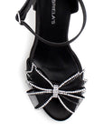 Vista de material shantung en zapatilla negra para mujer con pedreria en moño frontal y tacón delgado de 10cm