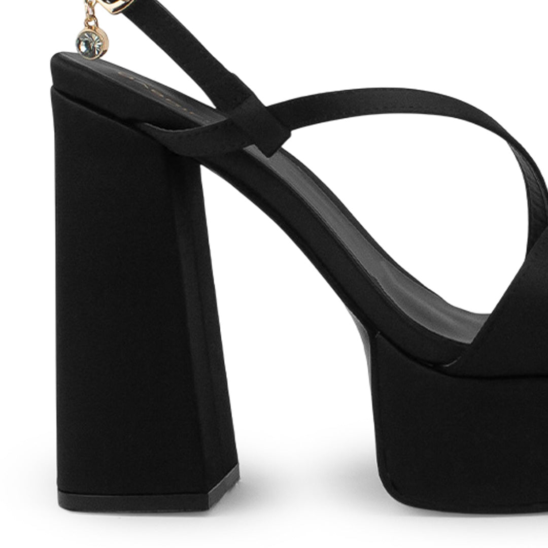 Vista trasera de tacón alto grueso de 14cm en zapatilla negra para mujer con tiras delgadas cruzadas colgante brillante de diseño descubierto