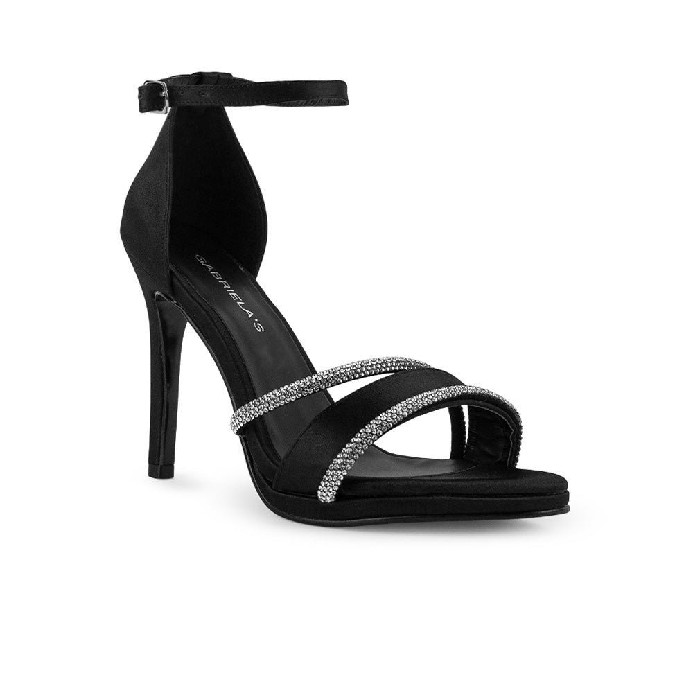 vista diagonal de zapatillas negras para dama con pulsera ajustable al tobillo y tiras delgadas de pedrería con tacón medio 10 cm 