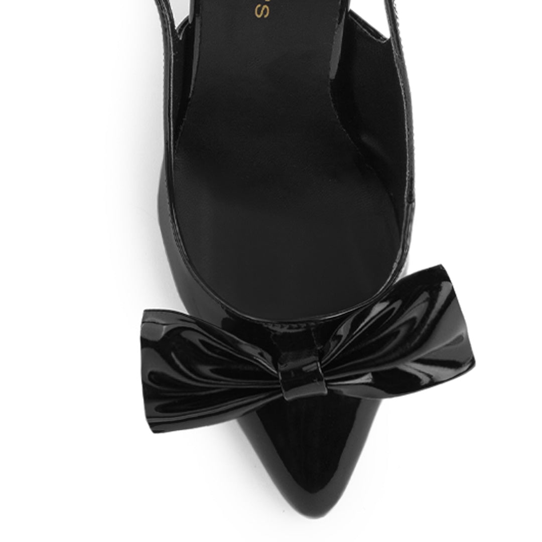 Vista de material charol en zapatilla destalonada tipo stiletto para mujer con moño en punta fina cerrada de tacón delgado de 8cm en color negro