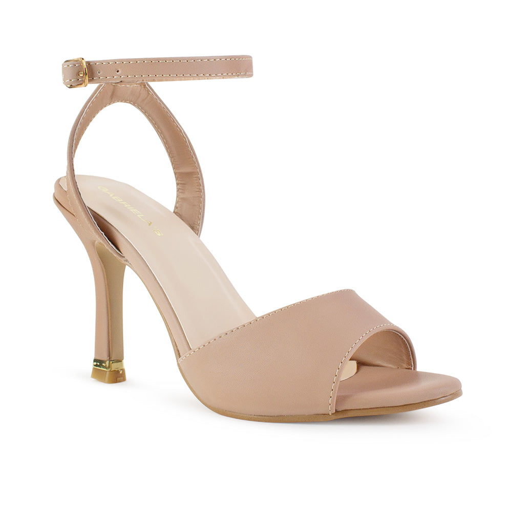 Vista diagonal de zapatilla nude de diseño descubierto para mujer con tacón delgado medio de 10cm y pulsera ajustable al tobillo con hebilla metálica