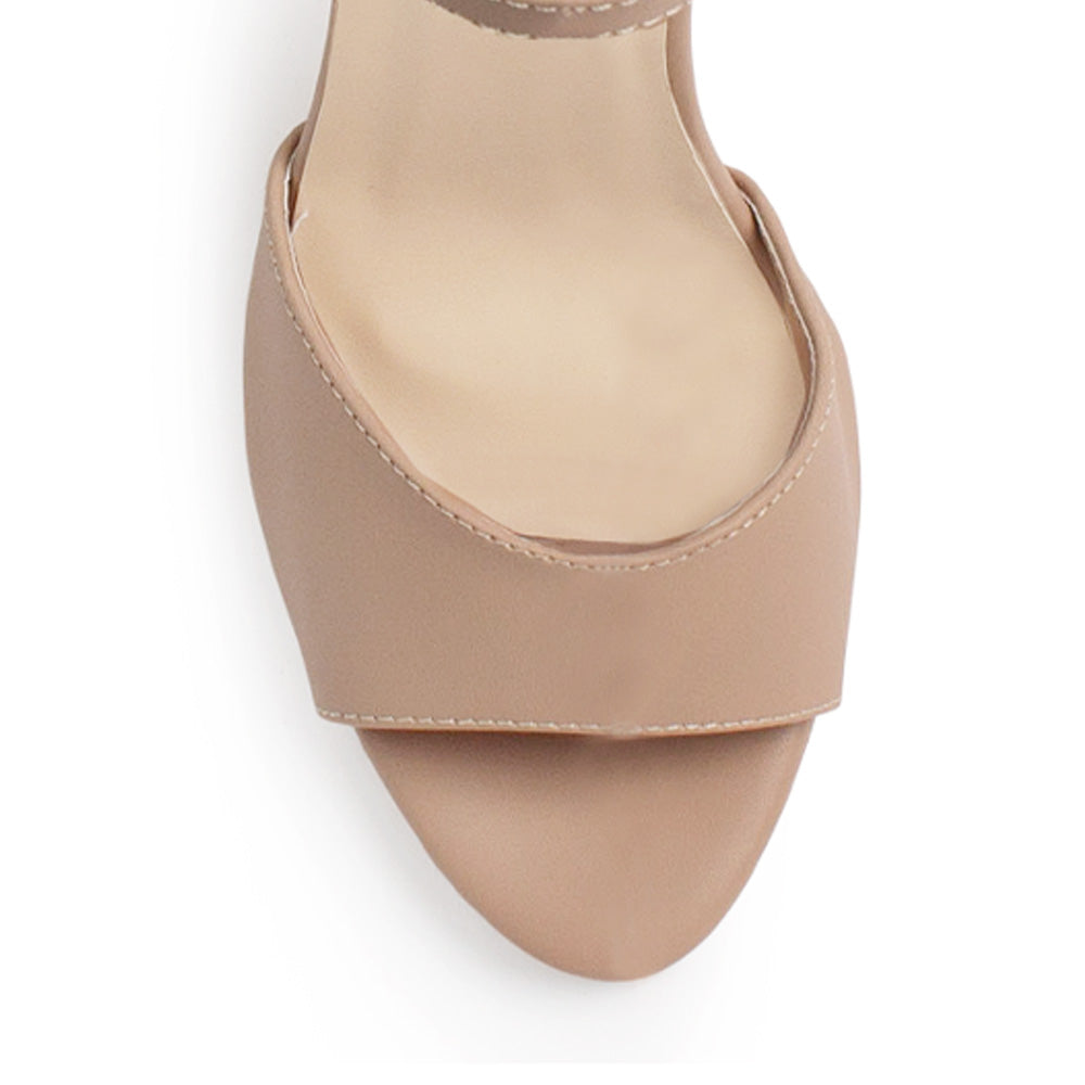 Vista de material cabra sintético en zapatilla nude para mujer de diseño descubierto con hebilla rectangular metálica en pulsera ajustable y tacón delgado medio de 10cm