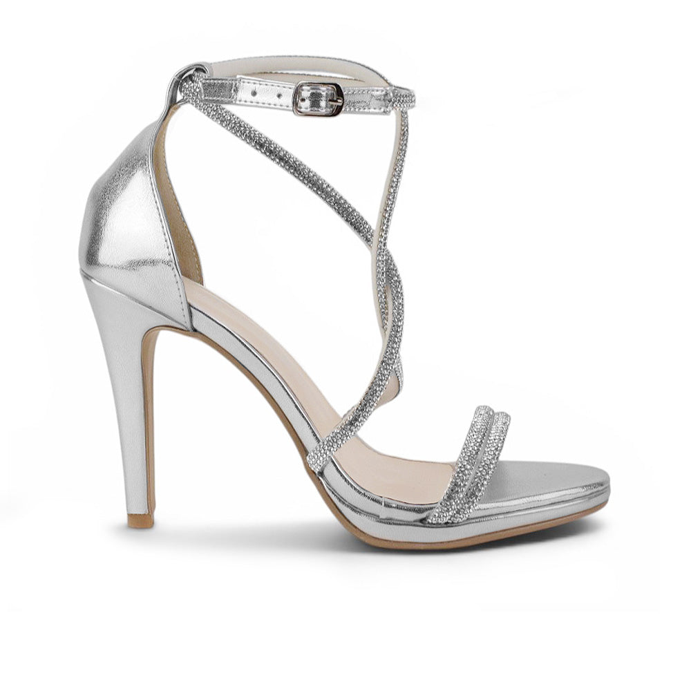 Vista lateral de zapatilla plateada para mujer de diseño descubierto con tiras de pedrería pulsera ajustable y tacón delgado de 10cm
