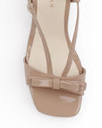 Vista de material charol en zapatilla nude de diseño descubierto para mujer con moño y tacón delgado de 8cm