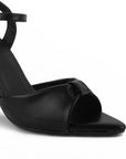 Vista a detalle de punta fina abierta en zapatilla negra para mujer con pulsera ajustable y tacón delgado medio de 10cm de diseño descubierto