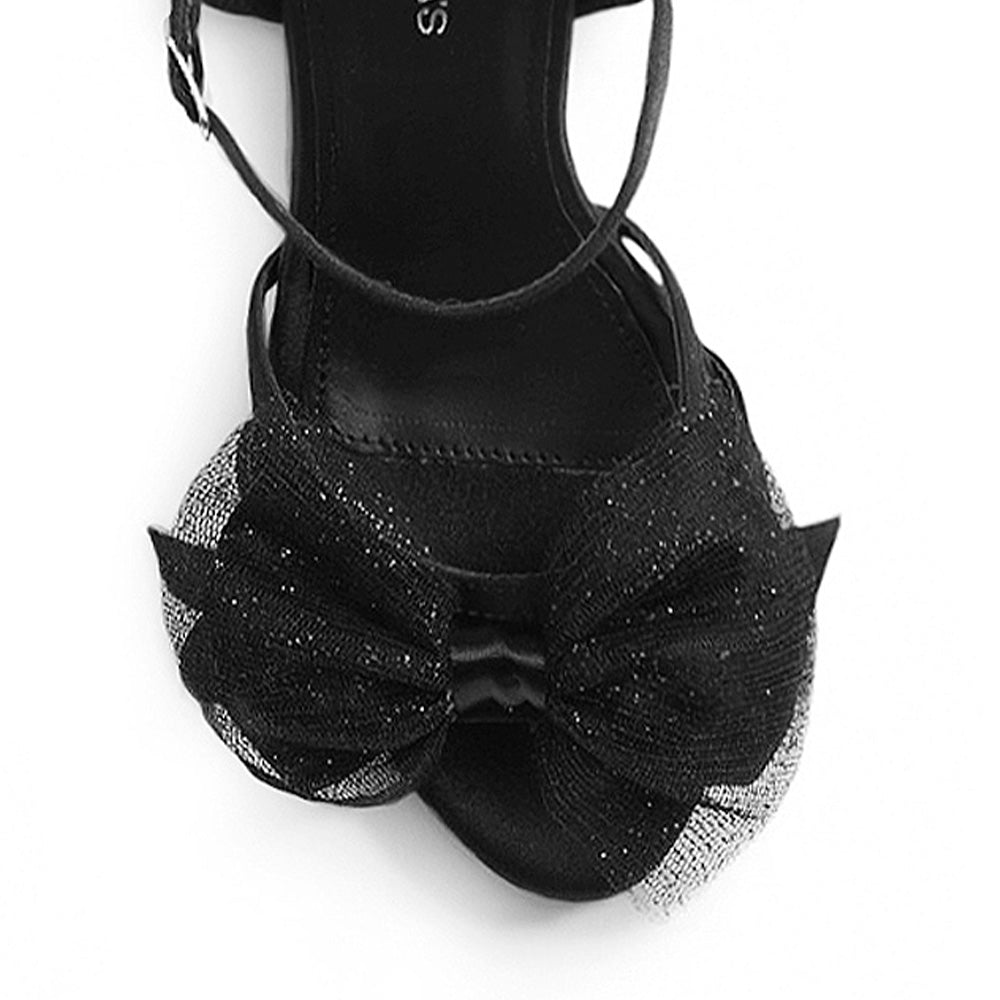 vista del detalle en el moño brilloso de zapatillas negras para dama con pulsera al tobillo y tacón alto 11cm 